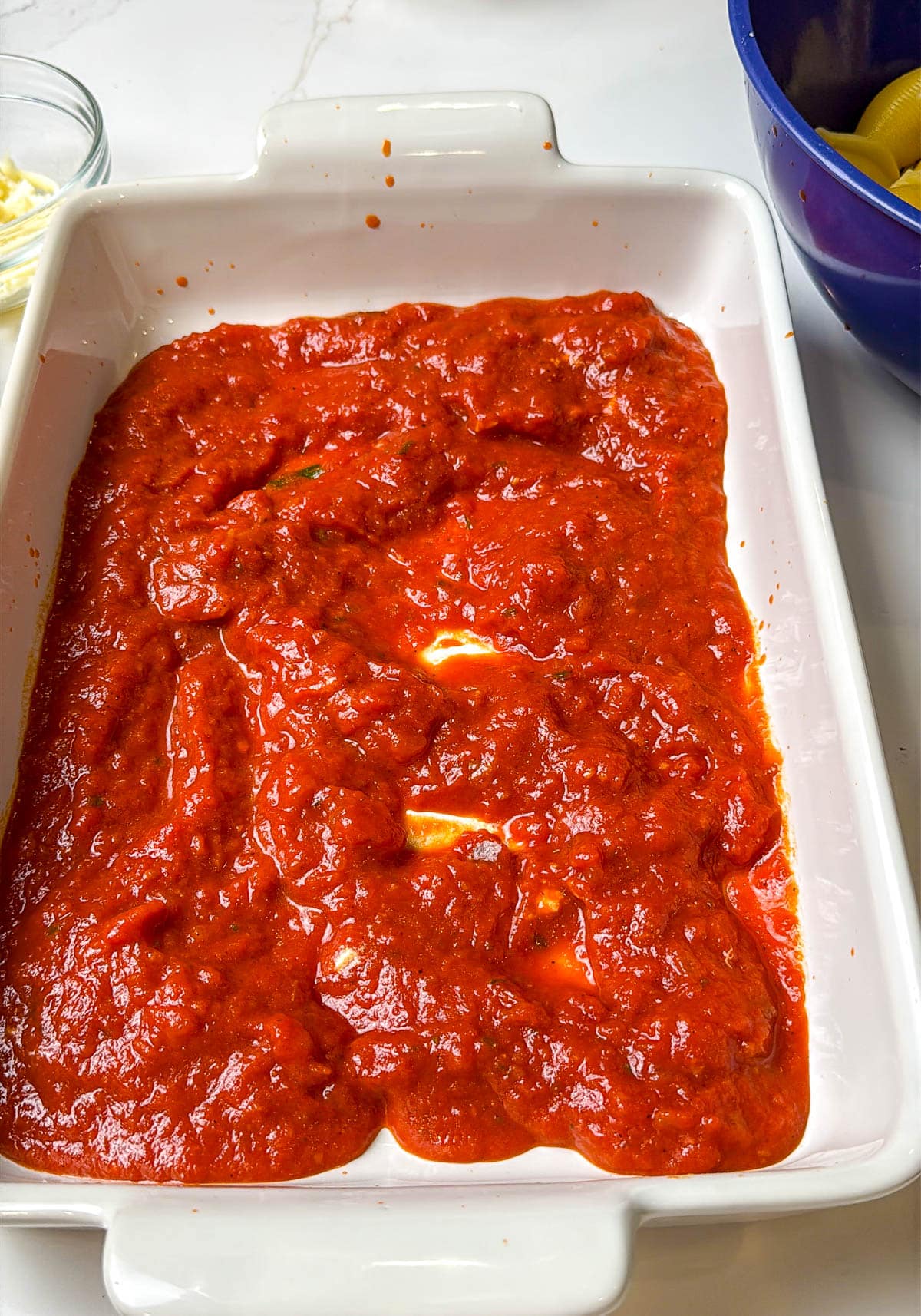 Marinara sauce coating the bottom of the 9x13 baking dish.