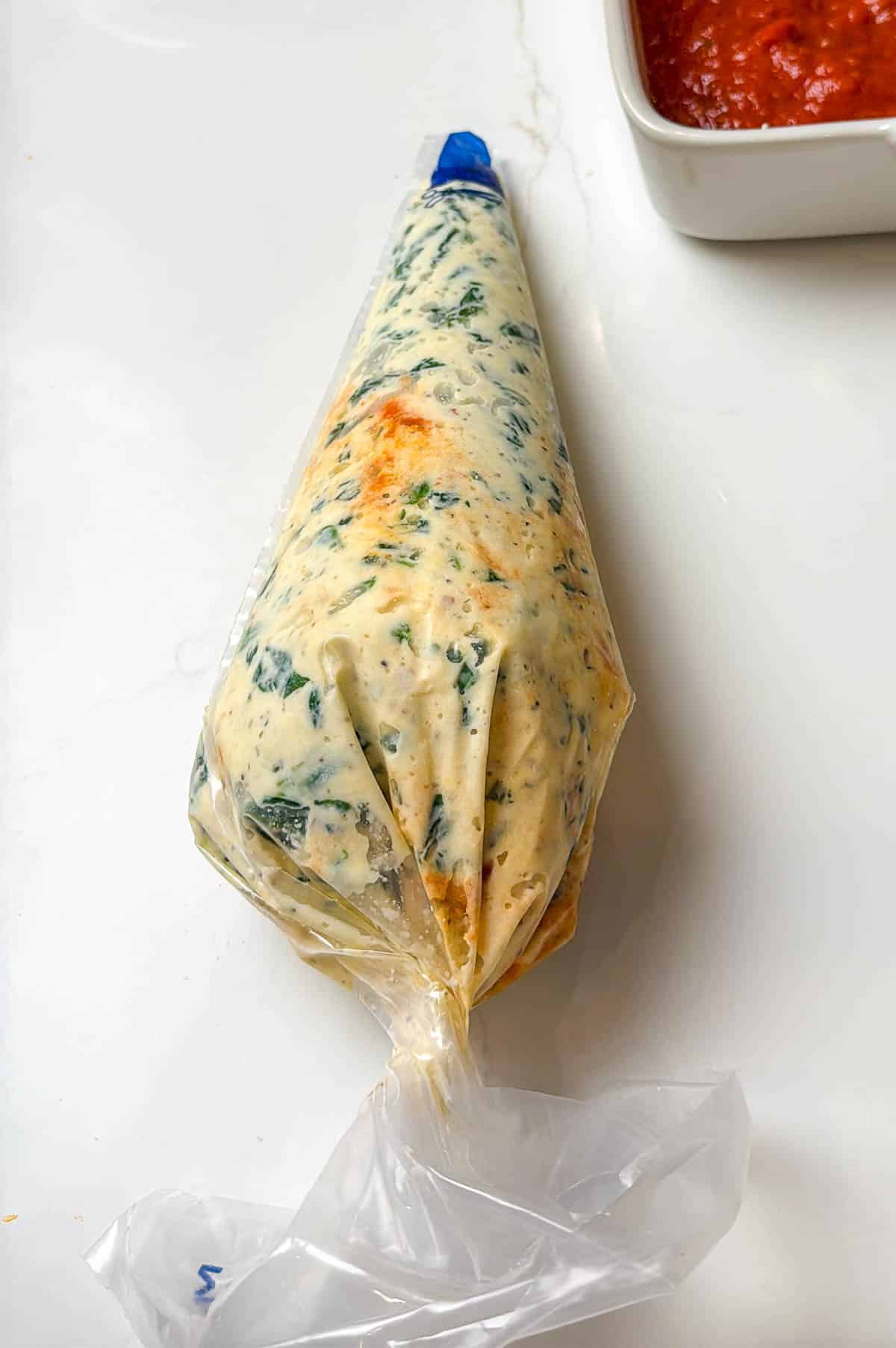 Piping bag is full, twisted closed, and the top is cut open to begin piping.