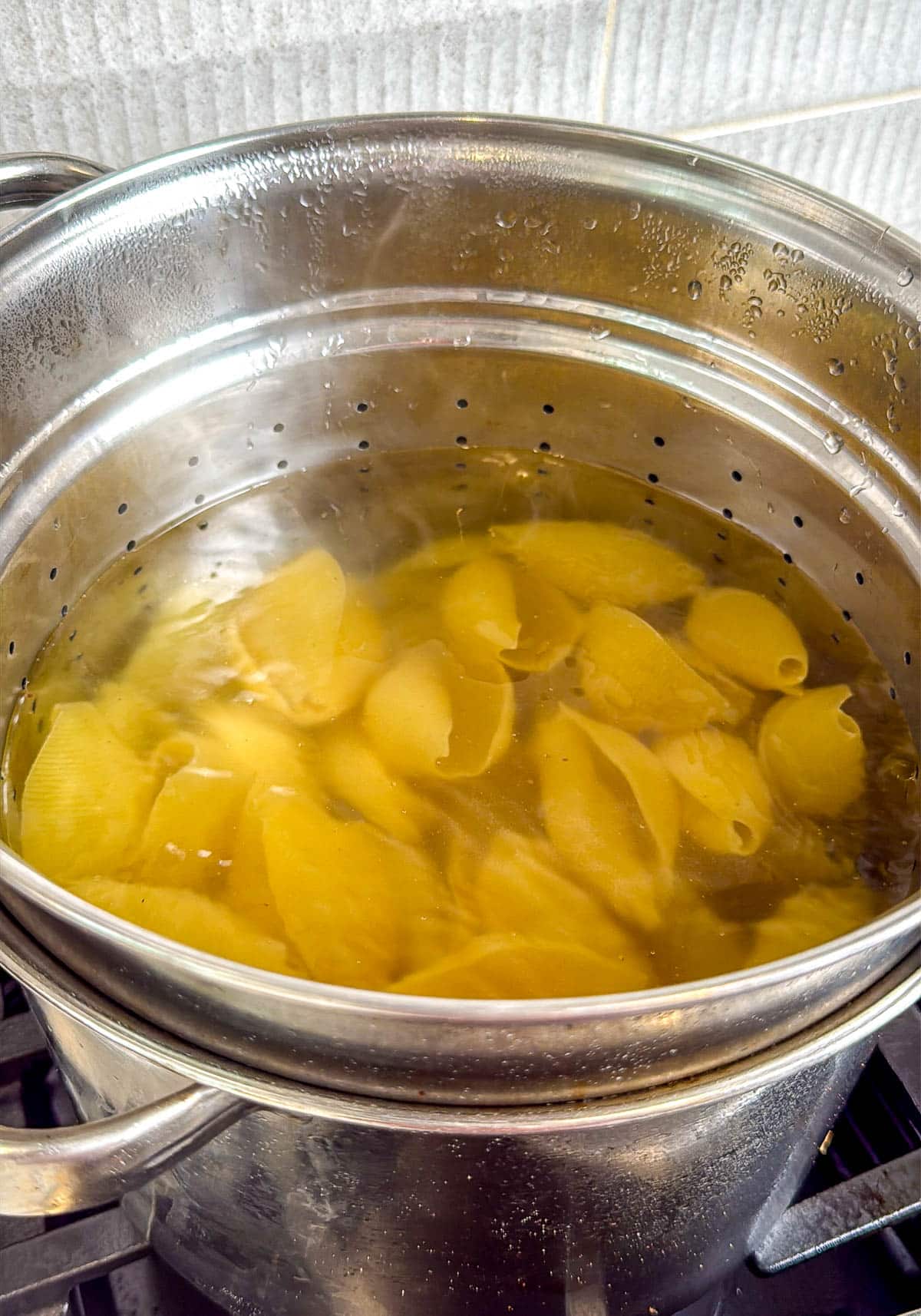 Jumbo pasta shells boiling in a large pot.