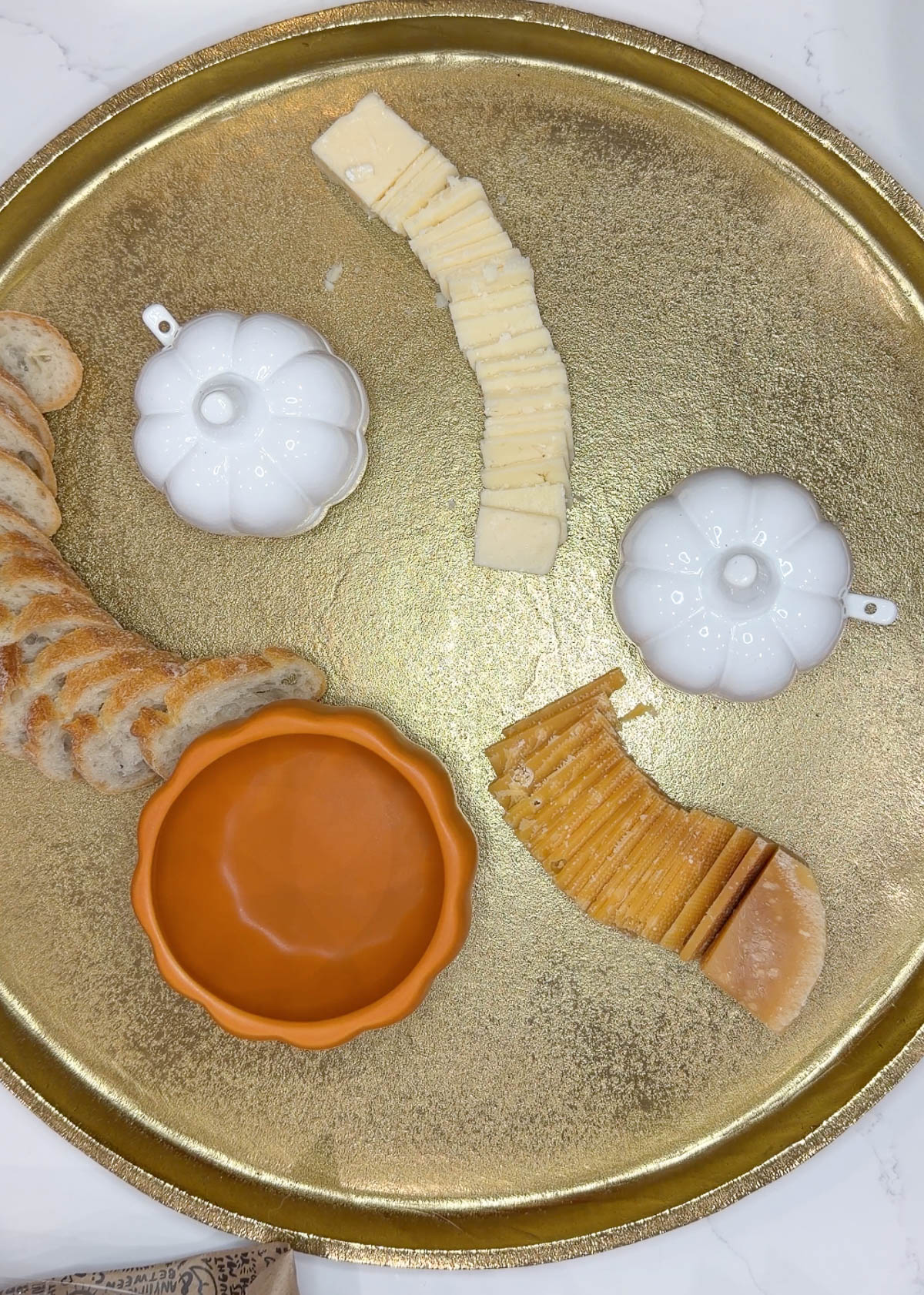 A gold tray with cut cheeses and bread on it.