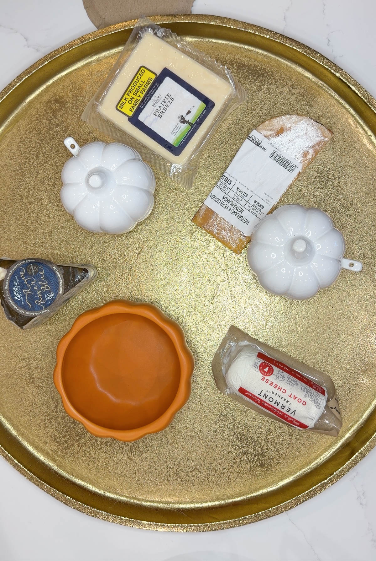 A gold tray with wrapped cheeses on it.