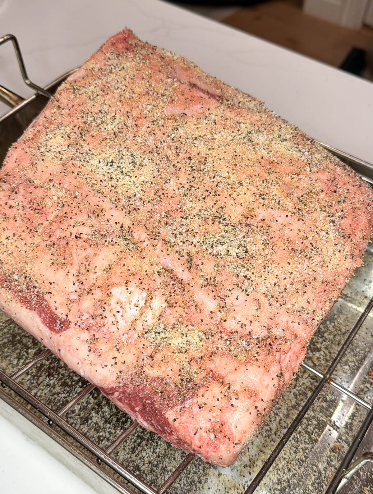 The fat cap side of the prime rib roast seasoned with salt, pepper, and garlic.