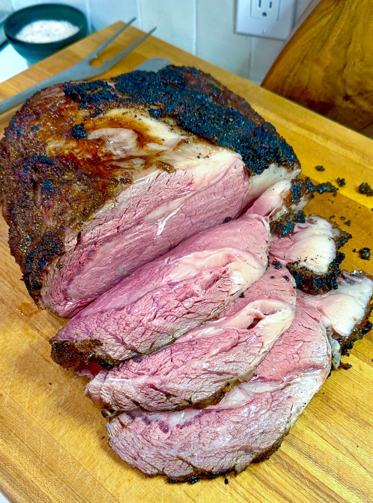 The finished reverse sear prime rib on a wooden cutting board sliced.