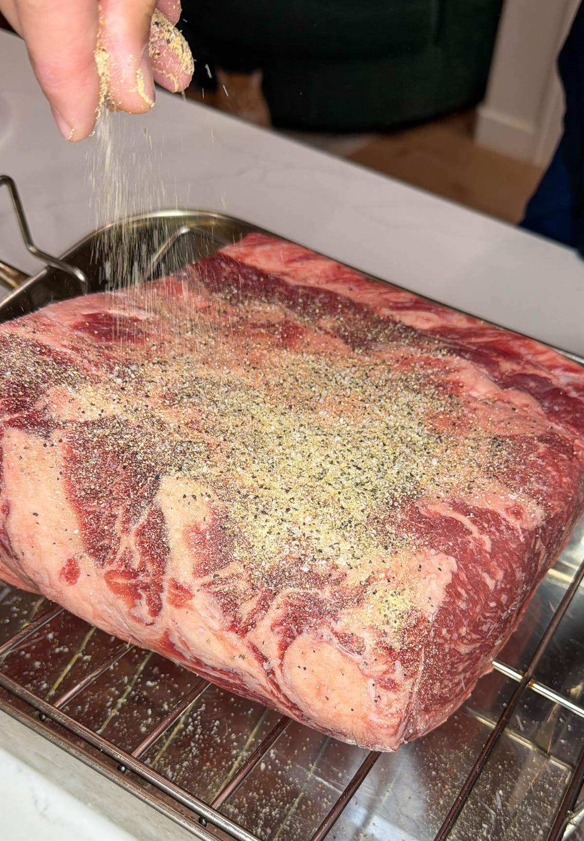 The underside of the prime rib roast seasoned with salt, pepper, and garlic.