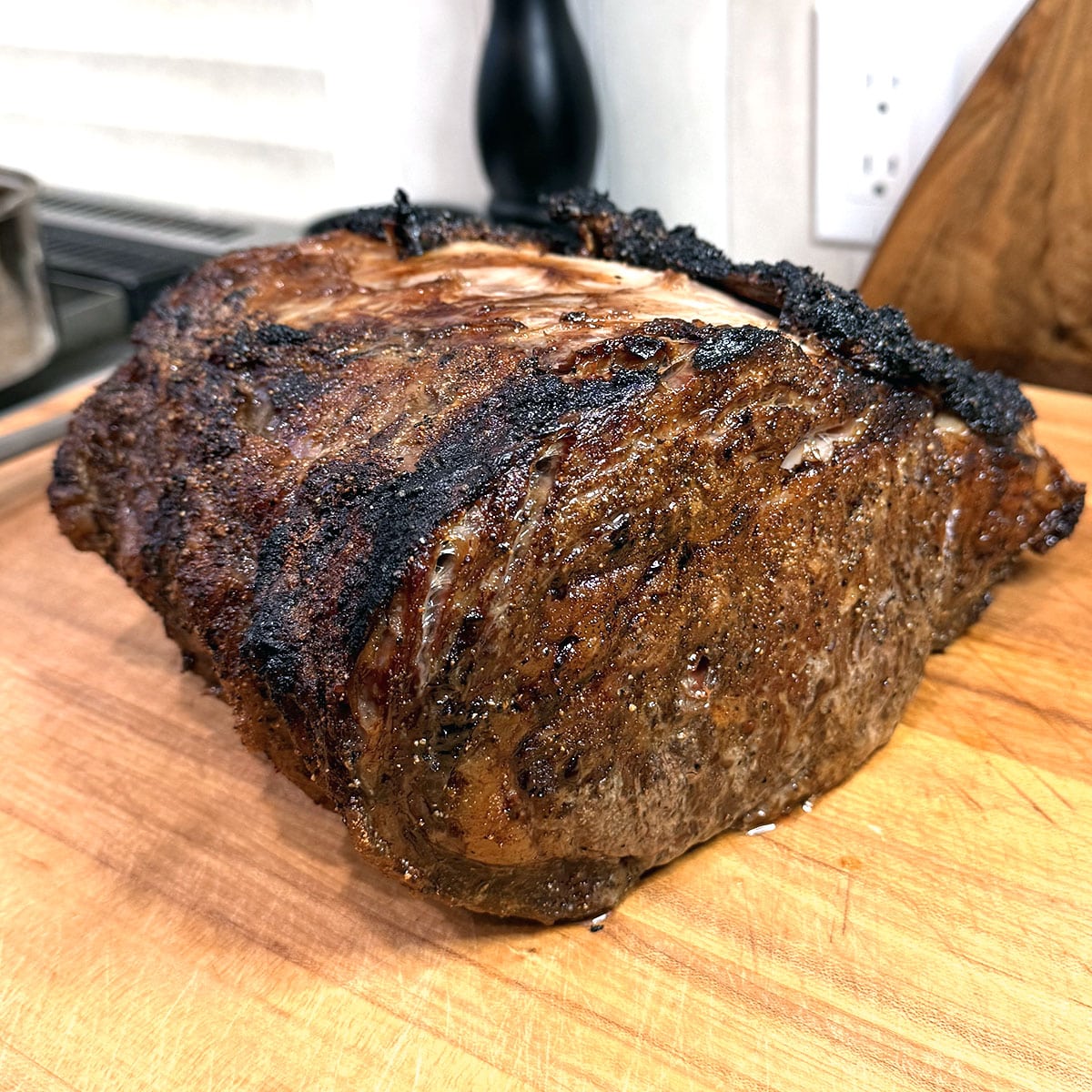 The finished, seared prime rib on a wooden cutting board before being sliced.