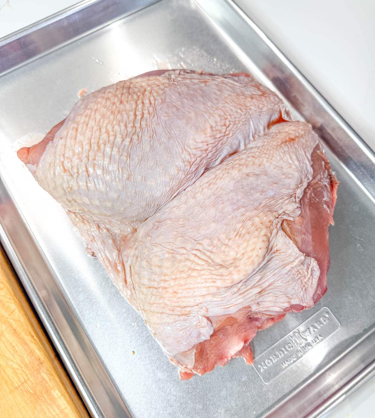 Turkey breast skin-side up on a baking sheet.