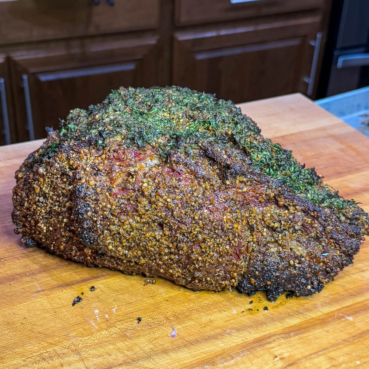 A whole smoked prime rib on a wooden cutting board.