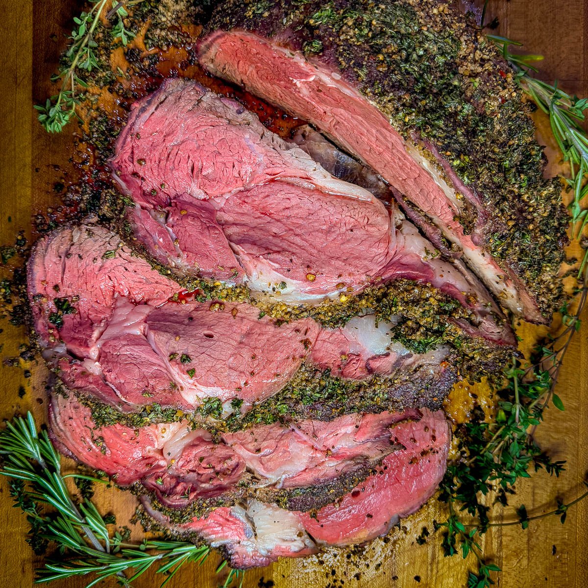 A close-up photo of a sliced, smoked prime rib on a wooden cutting board.