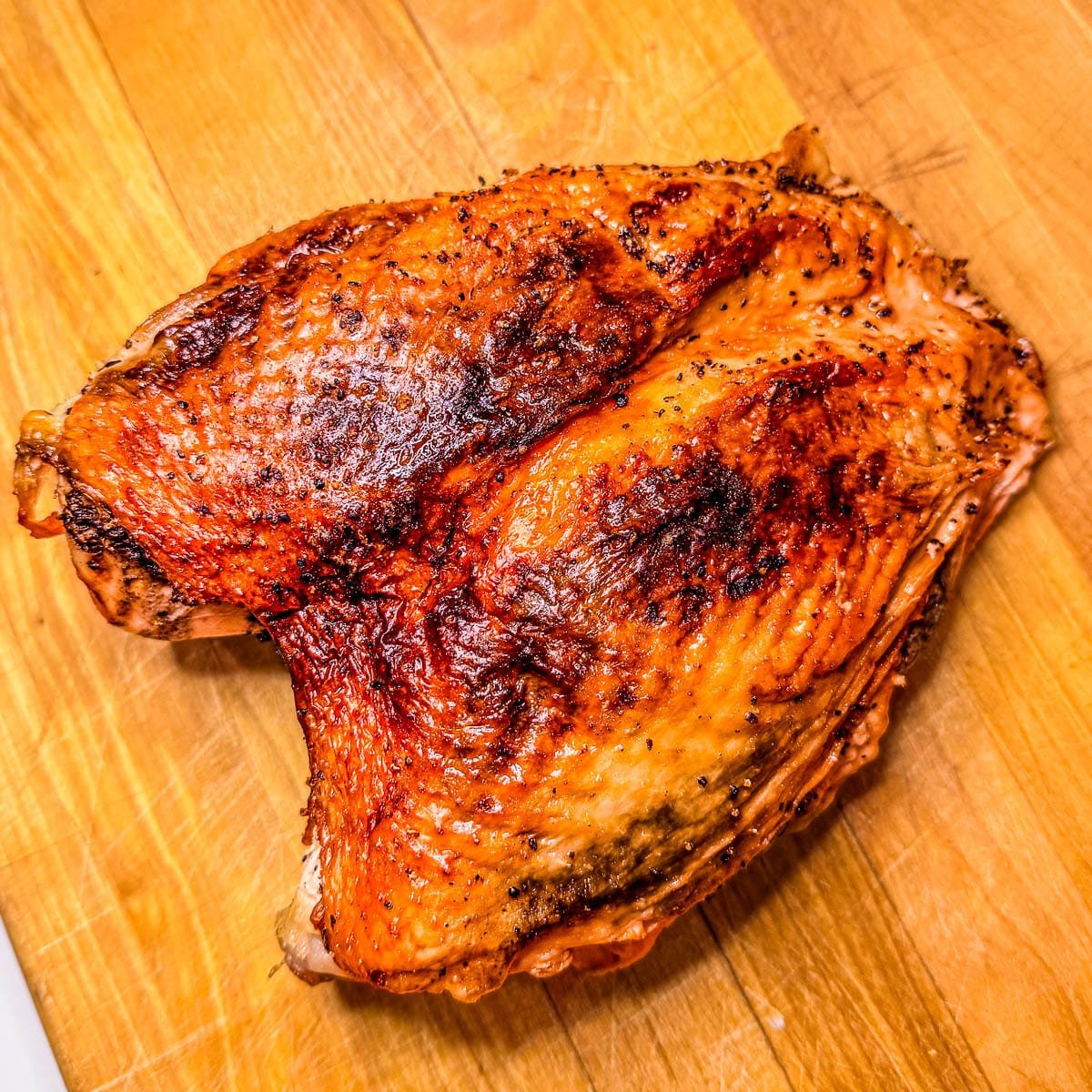 Roasted spatchcocked turkey breasts on a wooden cutting board.