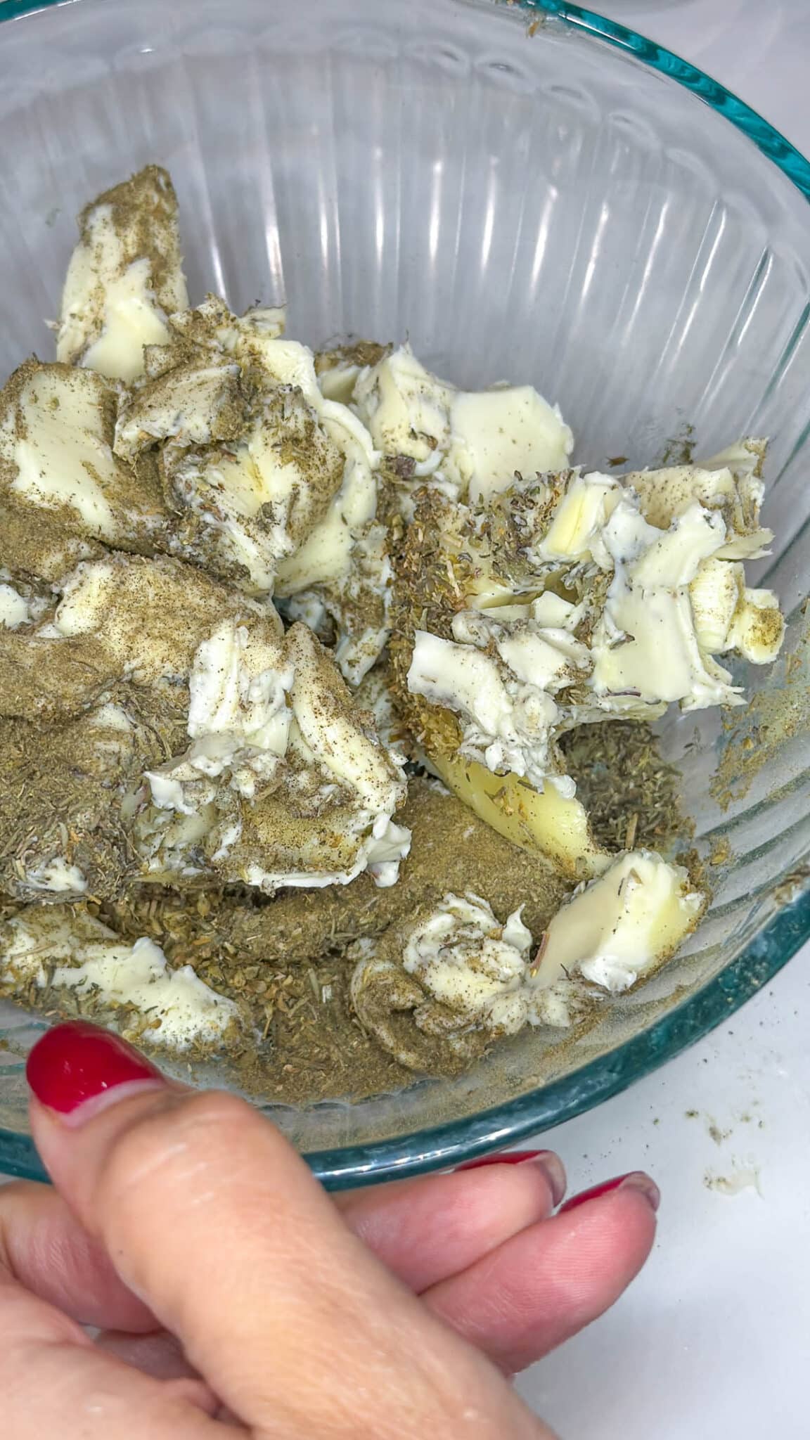 Butter broken up with seasoning in a small bowl.
