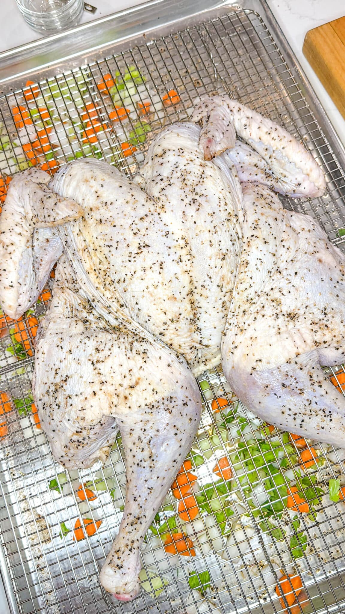 Spatchcocked turkey on top of the wire rack with the chopped vegetables underneath.