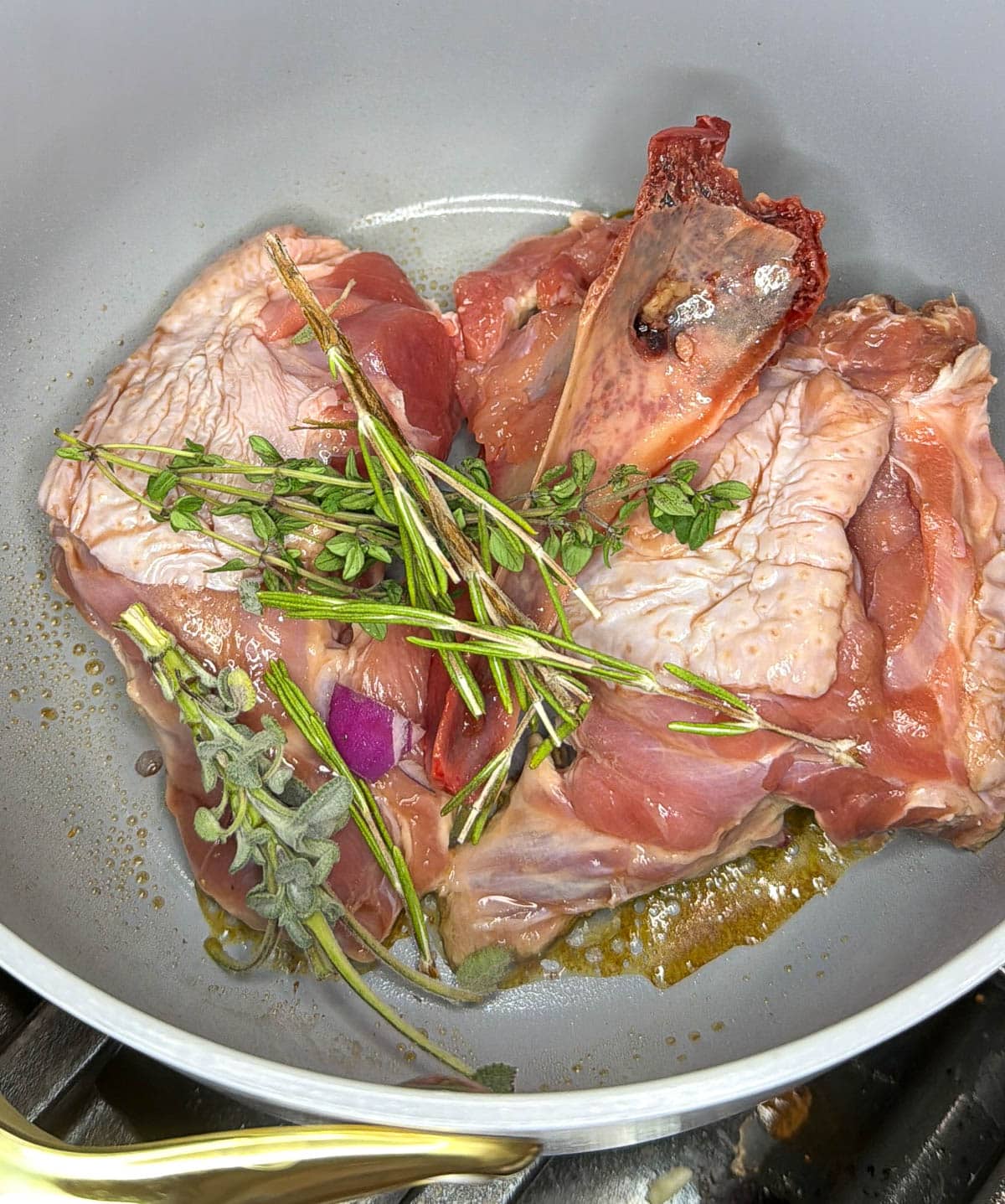 Turkey bones and giblets in a pot with fresh herbs on top.