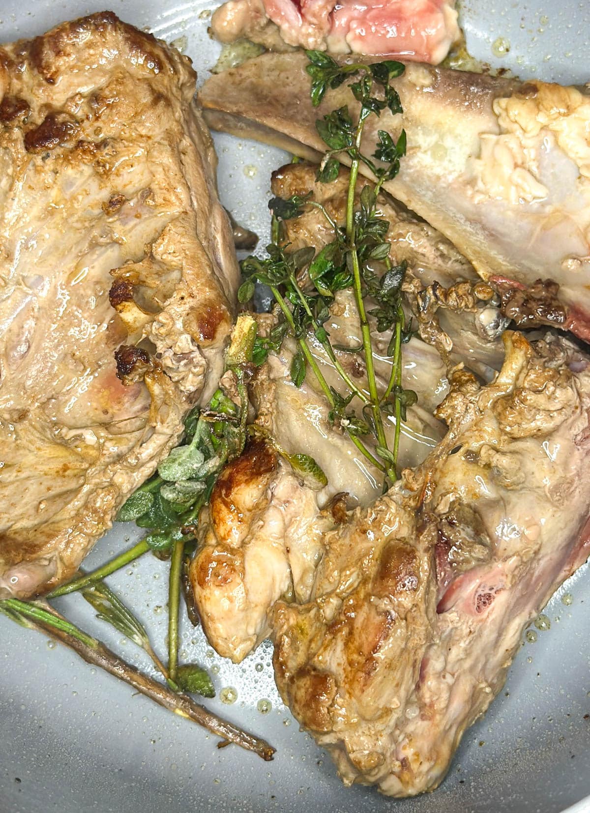 Cooked turkey bones and giblets in a pot with fresh herbs on top.