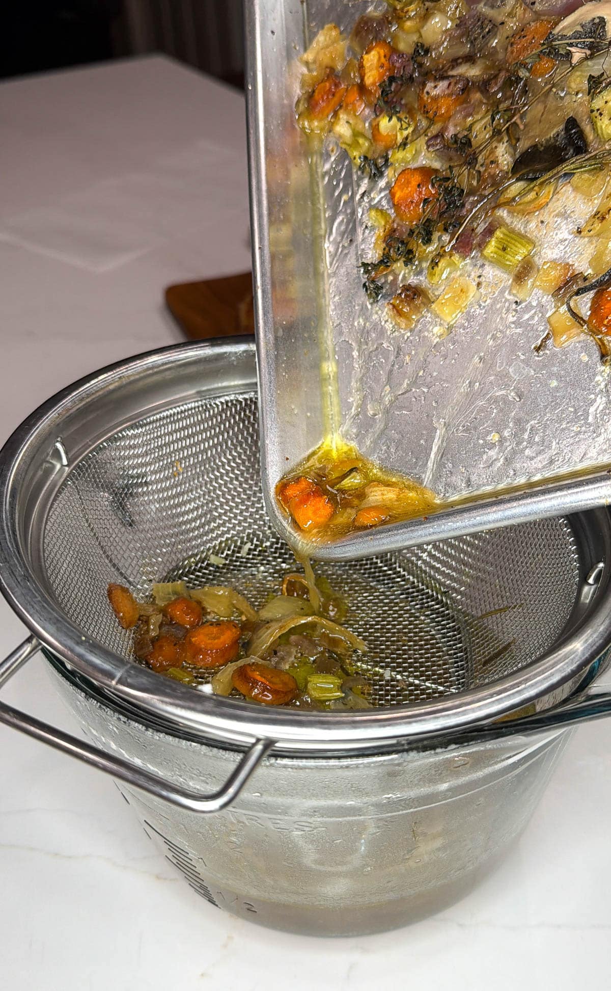 Roasted vegetables poured into a mest strainer.