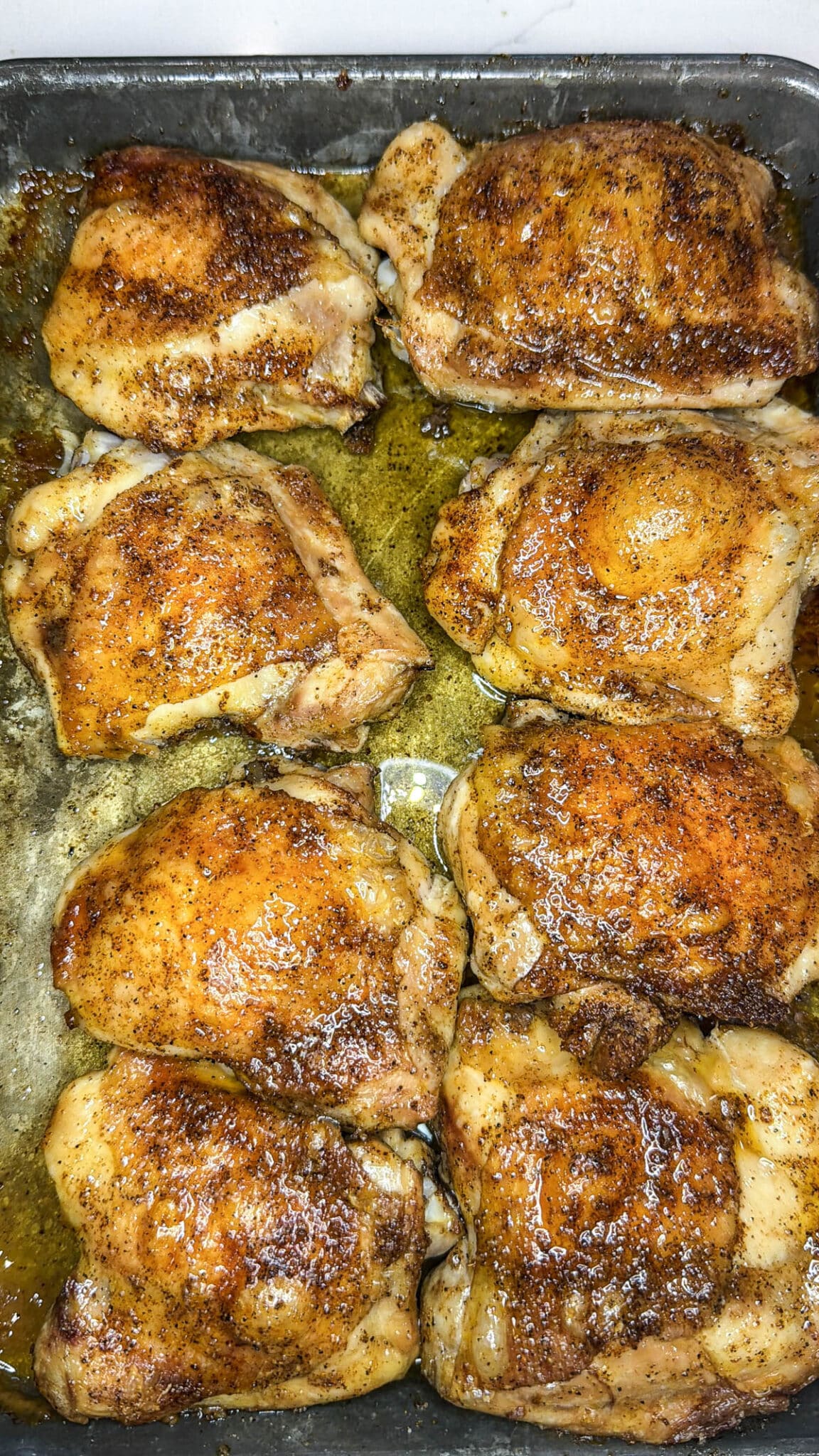 Baked chicken thighs on a sheet pan.