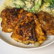 Close up of three crispy baked chicken thighs on a plate.