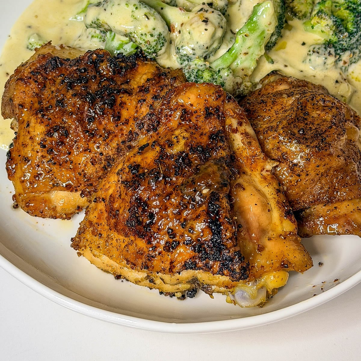 Three crispy chicken thighs on a dinner plate.