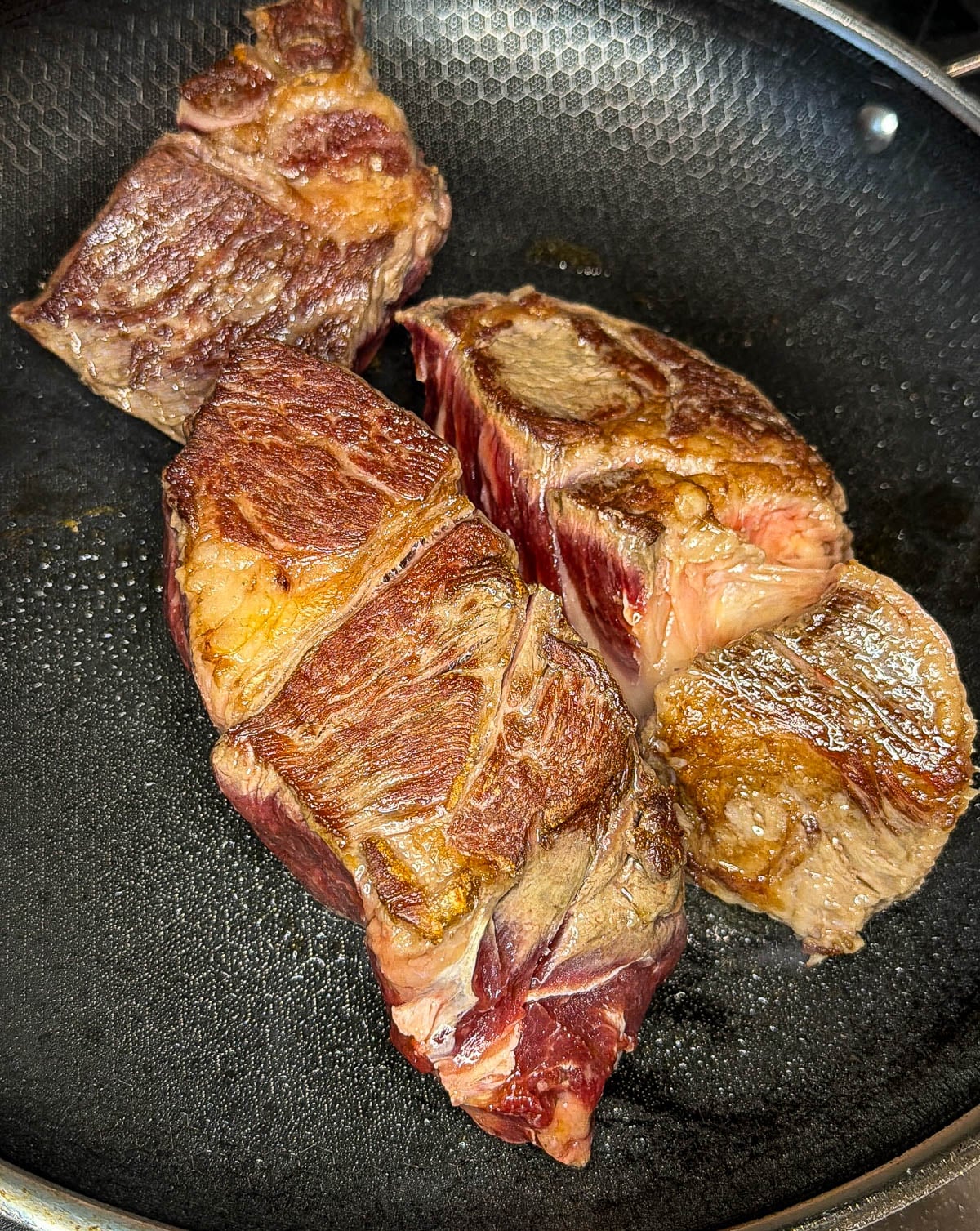 Searing chuck roast in a black pan.