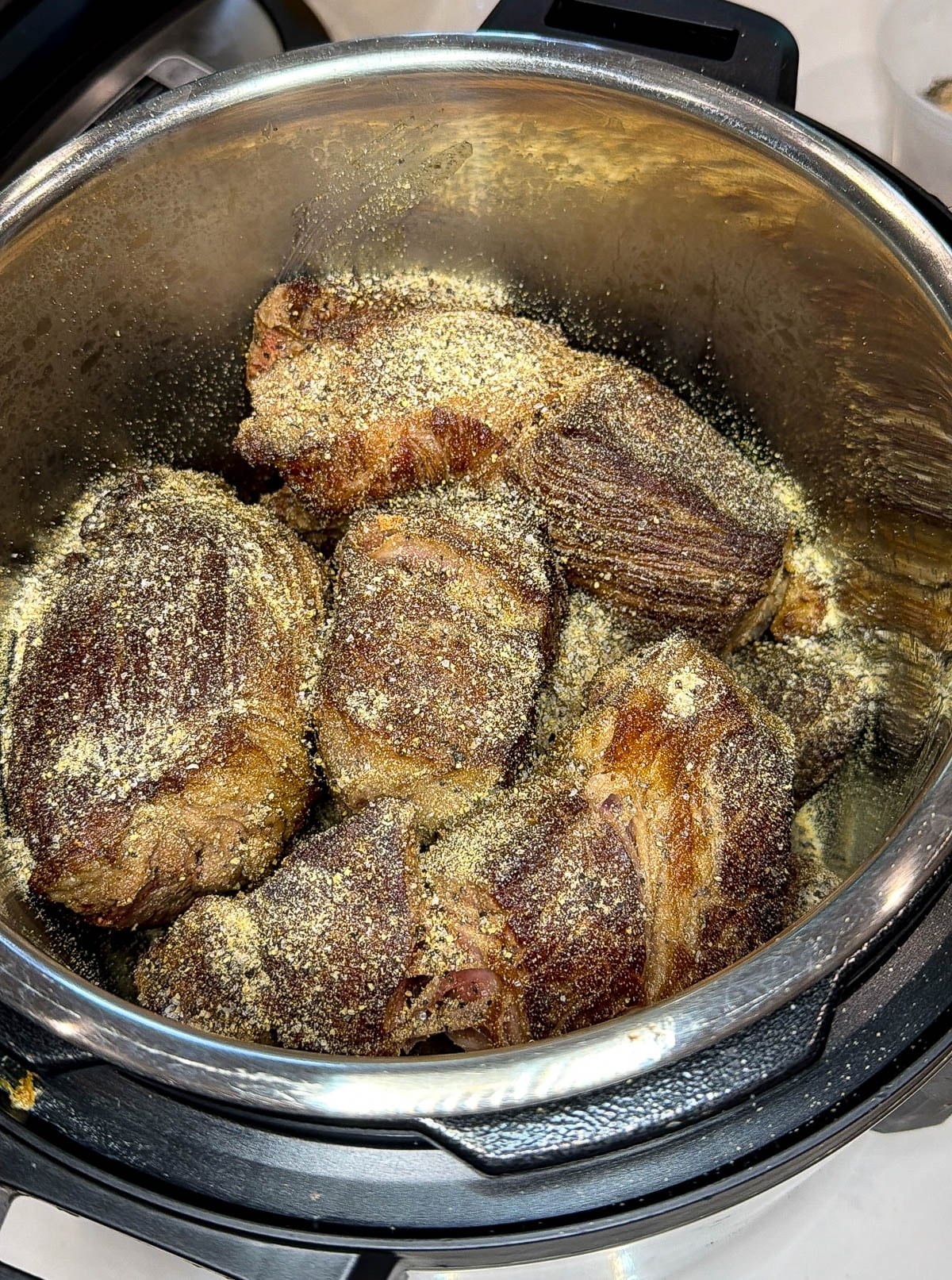 Chuck roast in an instant pot seasoned with salt and pepper.