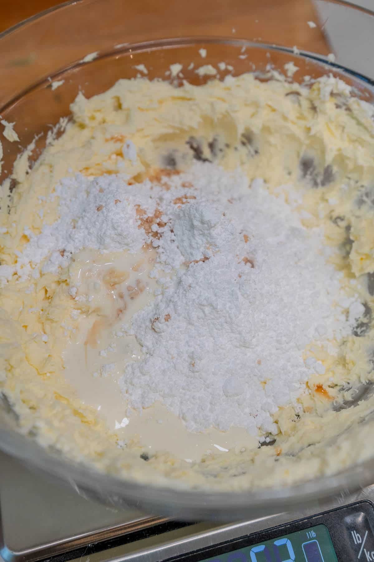Making cinnamon roll frosting in a clear glass bowl.