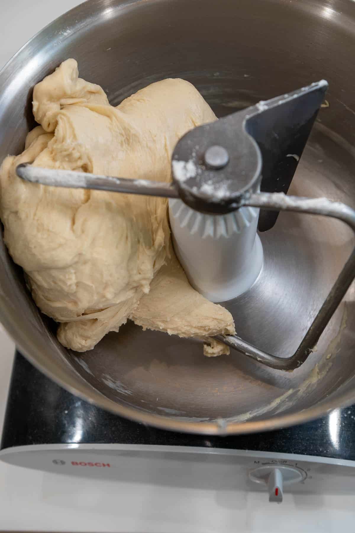 Sourdough discard cinnamon roll dough in a stand mixer with the dough hook attached.