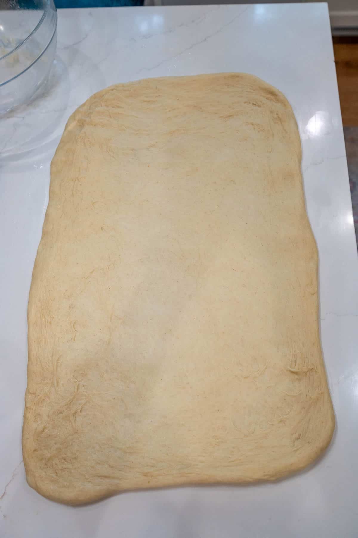 Sourdough cinnamon roll dough rolled out into a rectangle on a countertop.