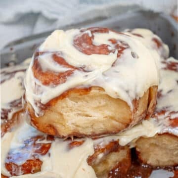 Frosted cinnamon roll on top of a pan of other cinnamon rolls.