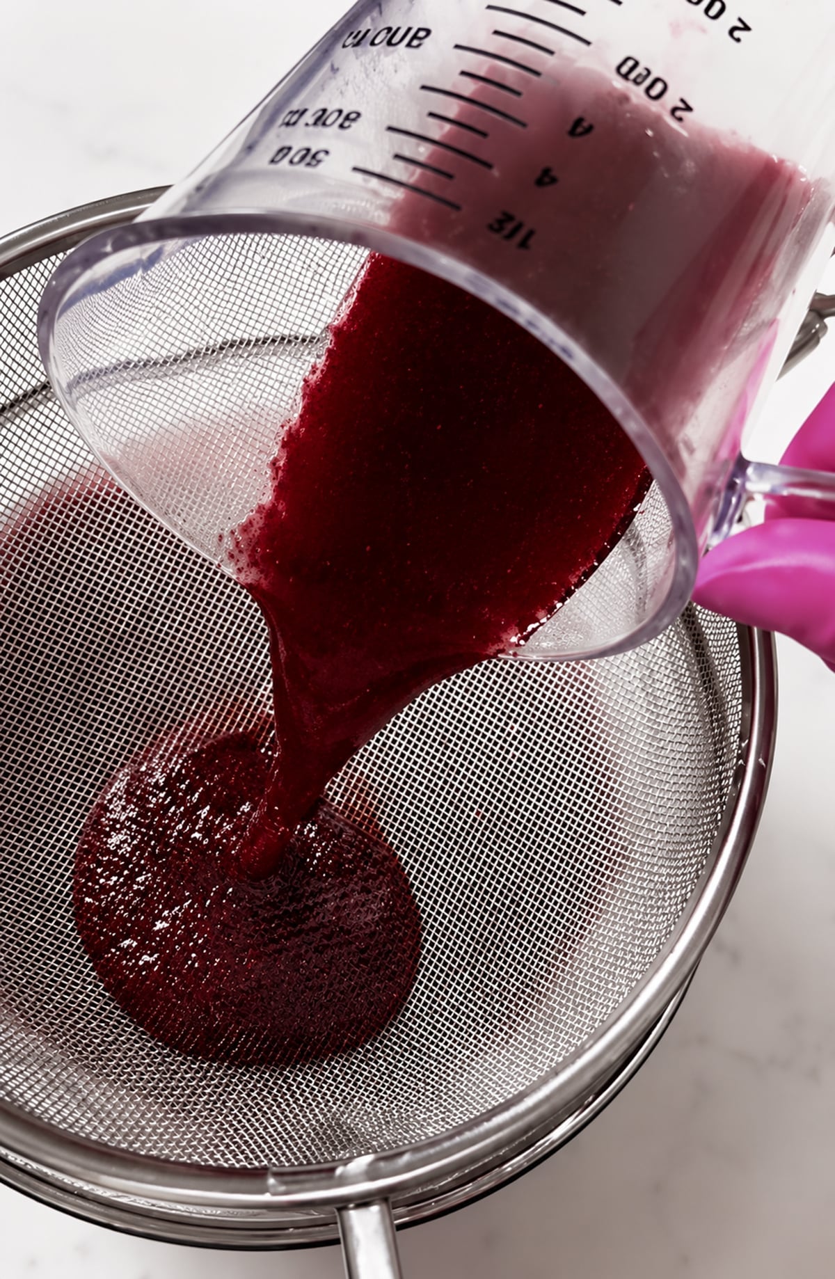 Straining spiced wine through a mesh strainer.