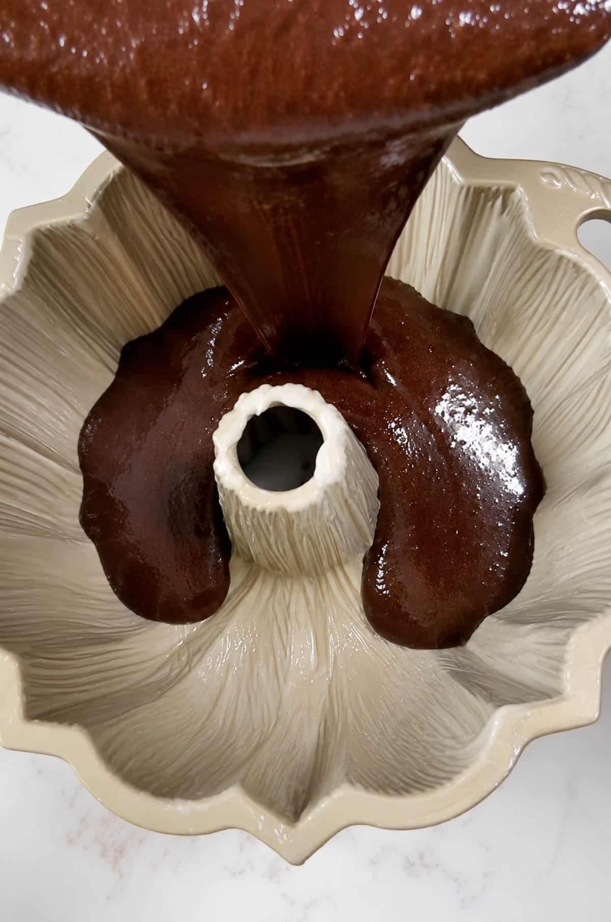 Pouring wine cake batter into a gold bundt cake pan