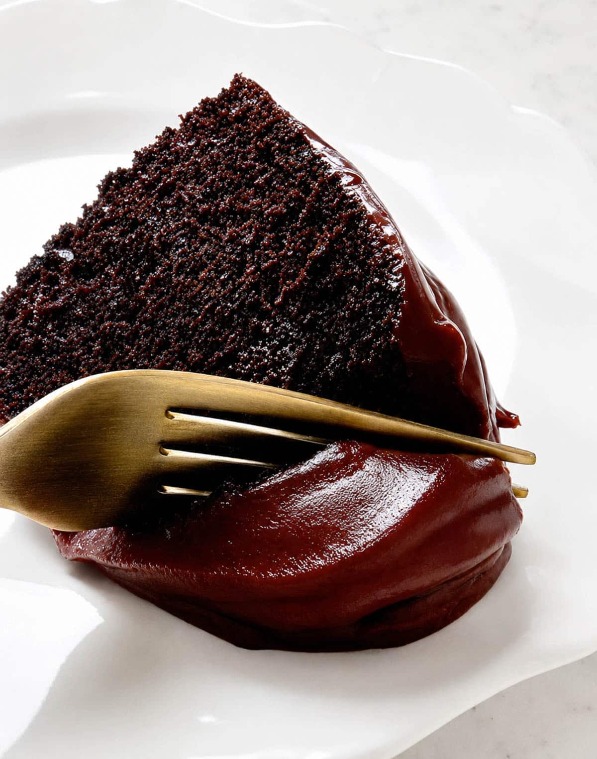 Fork cutting into a slice of red wine bundt cake on a white plate