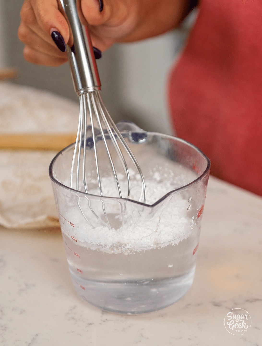 Whisking cornstarch and water together in a glass measuring cup to make a slurry for apple filling