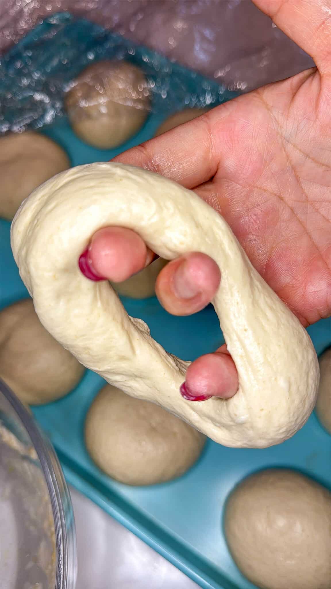 Sourdough discard bagel dough being shaped into a bagel.