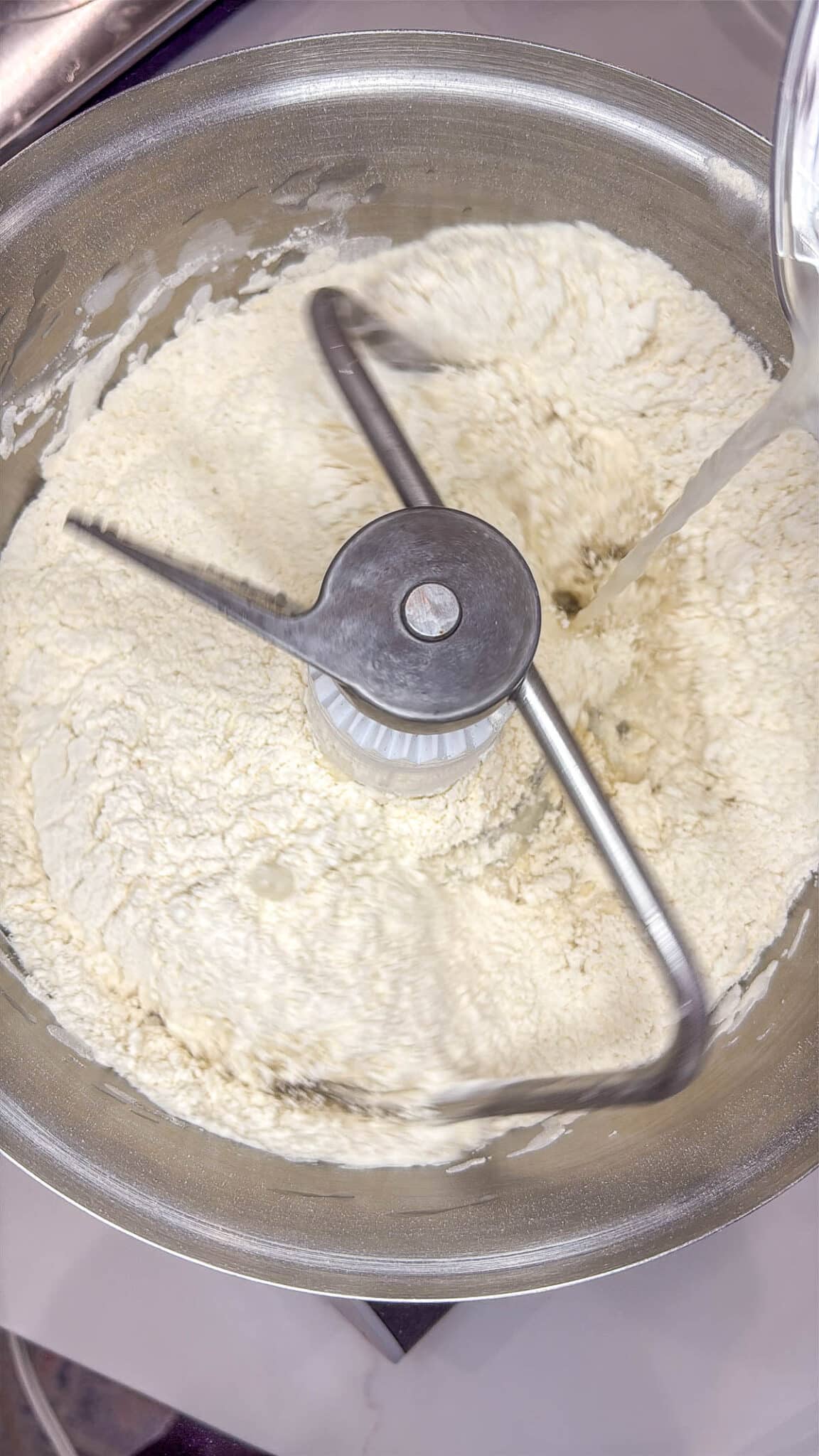 Sourdough discard bagels in a stand mixer with the dough hook attached.