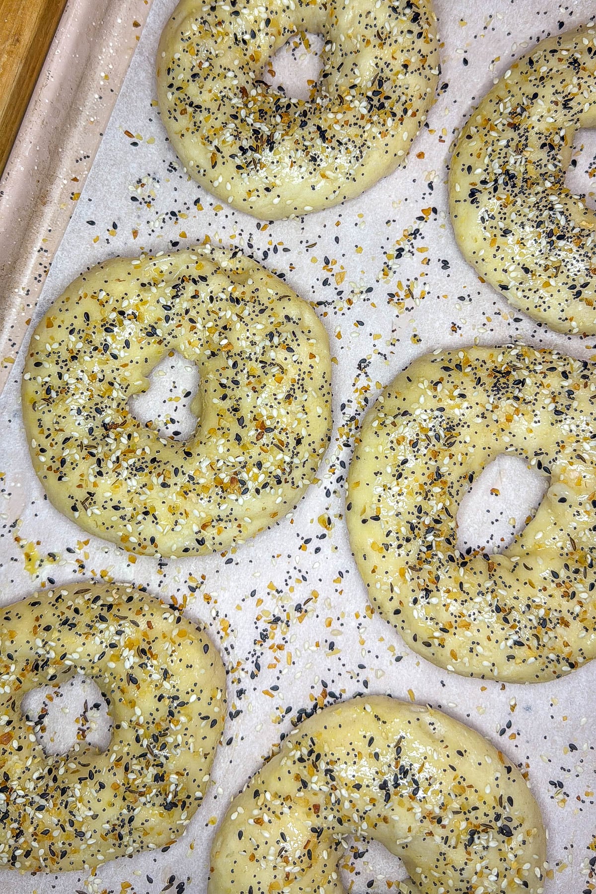 Sourdough discard bagels being topped with everything bagel seasoning before baking.