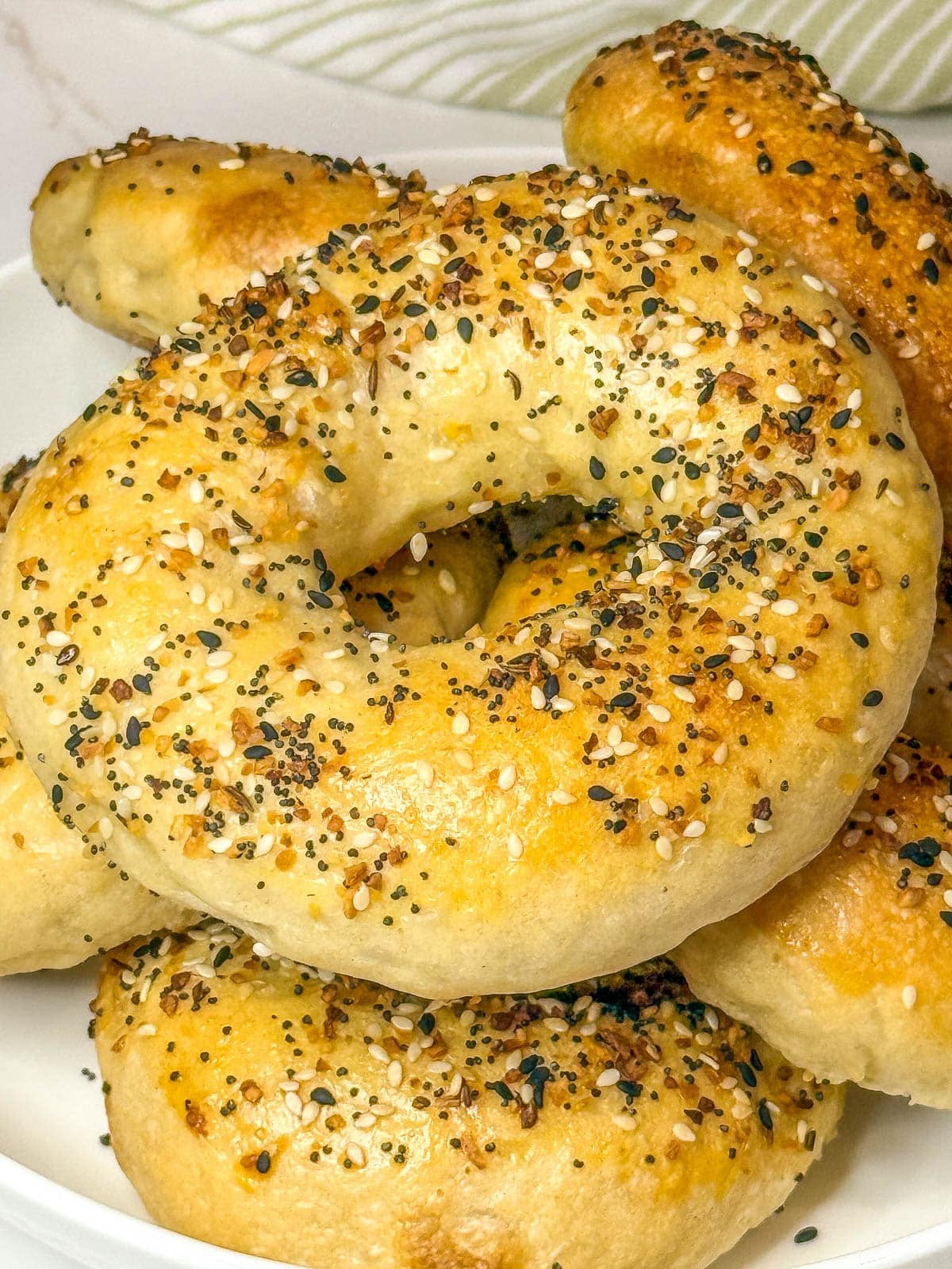 Sourdough discard bagels piled high on a plate.