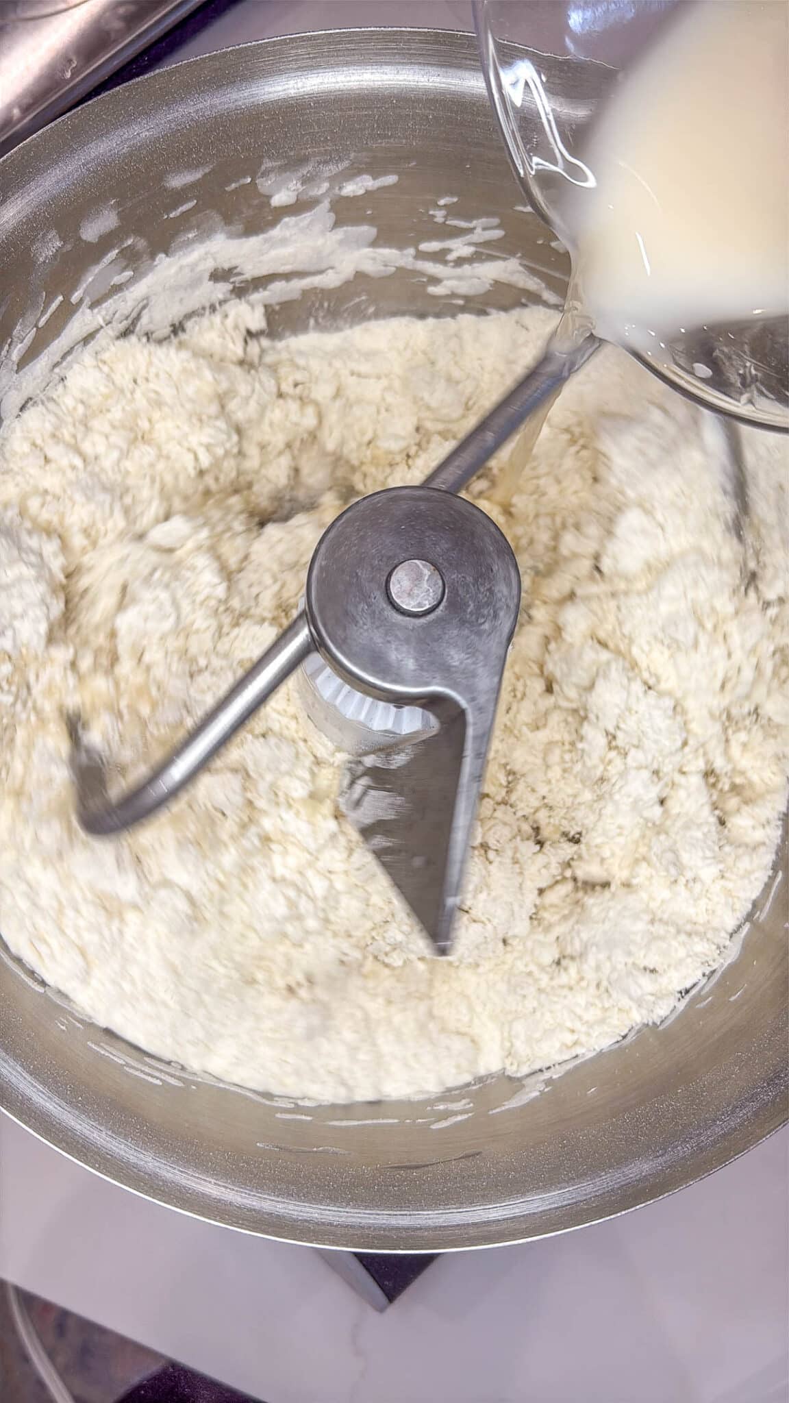 Sourdough discard bagel dough ingredients in the bowl of a stand mixer with the dough attachment.