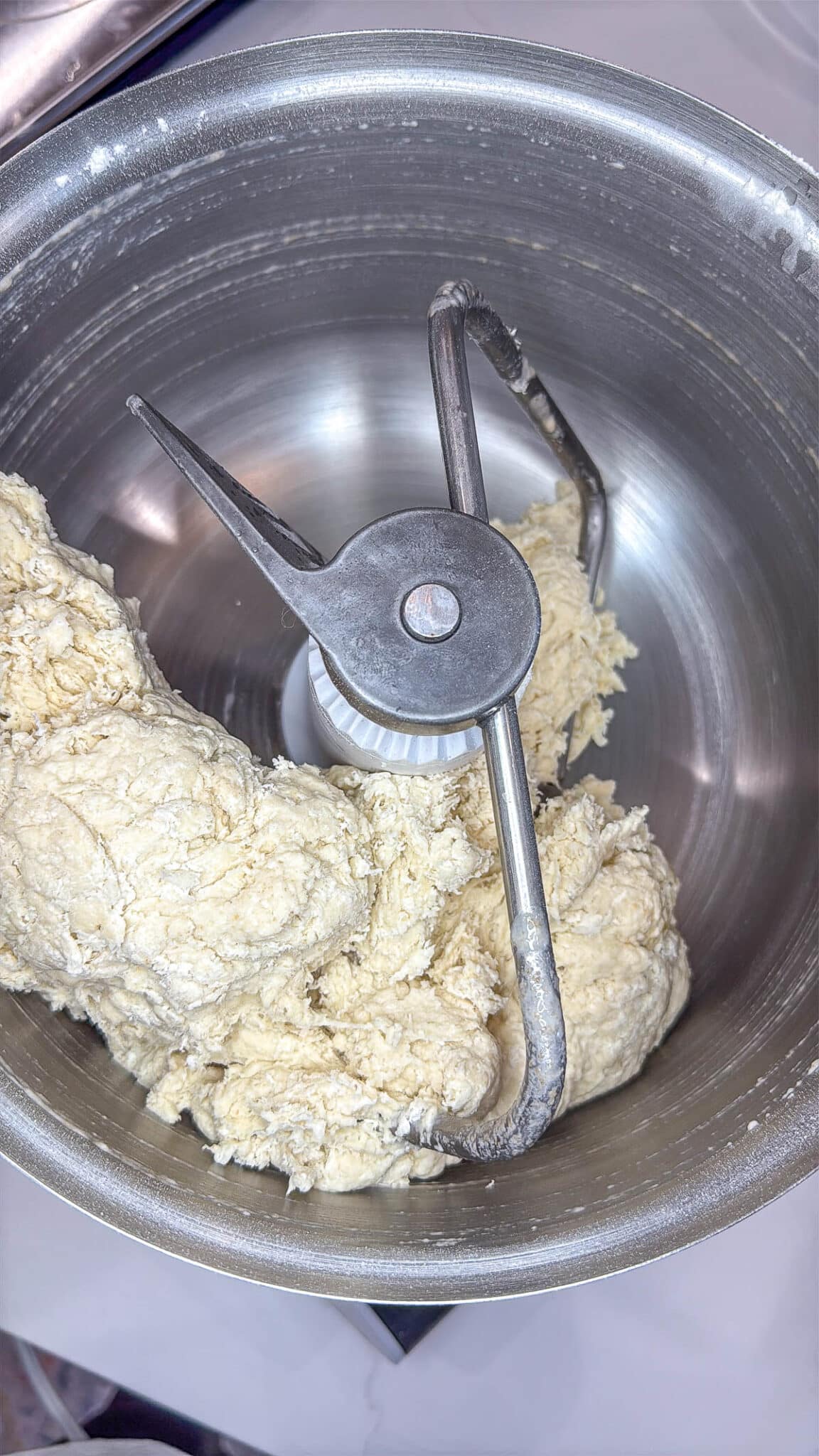 Sourdough discard bagel dough ingredients in the bowl of a stand mixer with the dough attachment.
