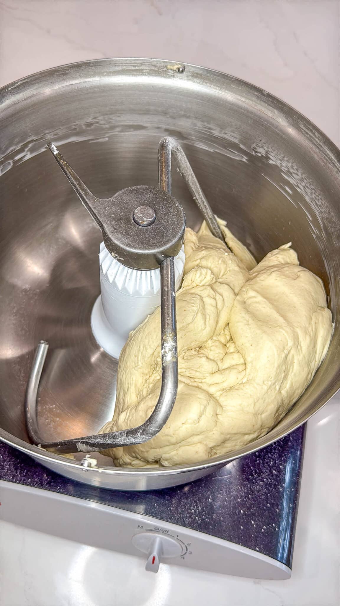 Sourdough discard bagel dough ingredients in the bowl of a stand mixer with the dough attachment.