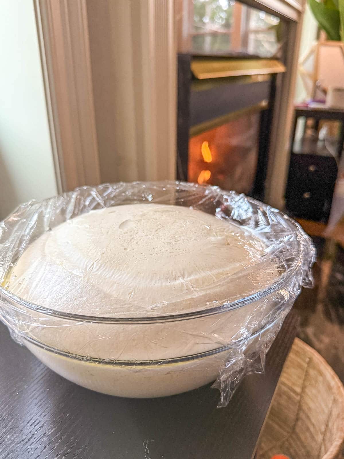 Sourdough discard dough ball in a clear glass bowl covered in plastic wrap.