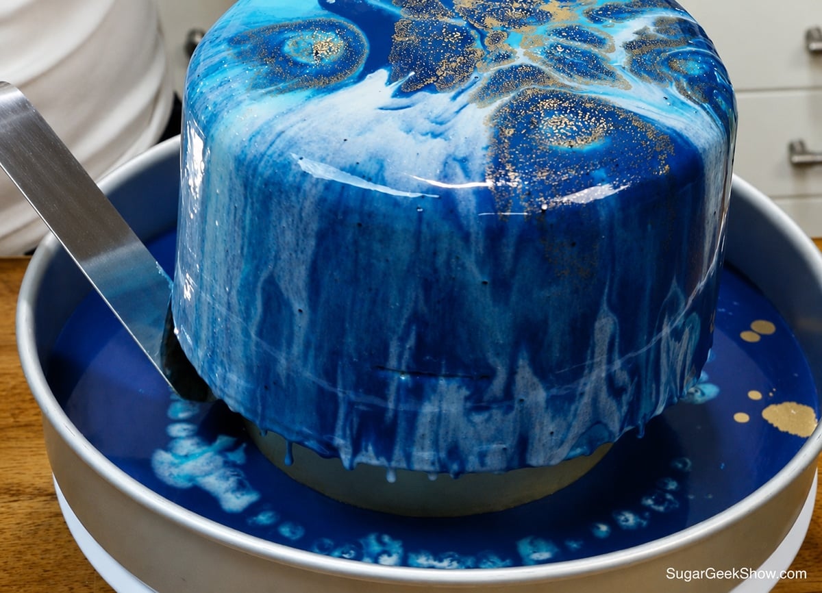 Using an offset spatula to trim off excess glaze drips.
