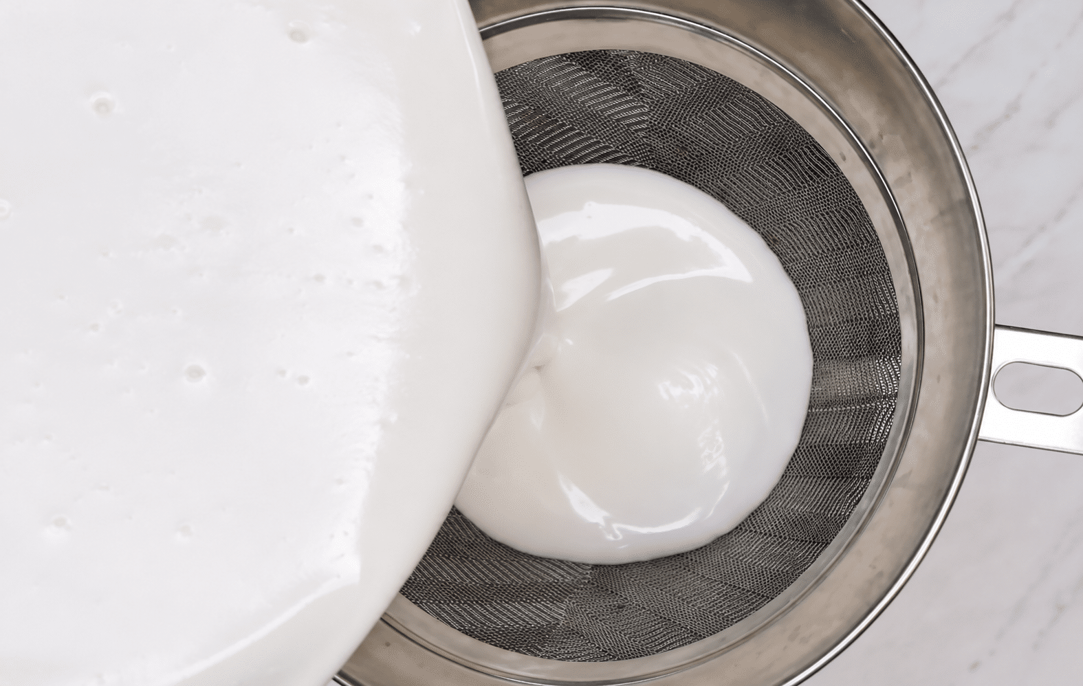 Straining the glaze with a fine mesh sieve. 