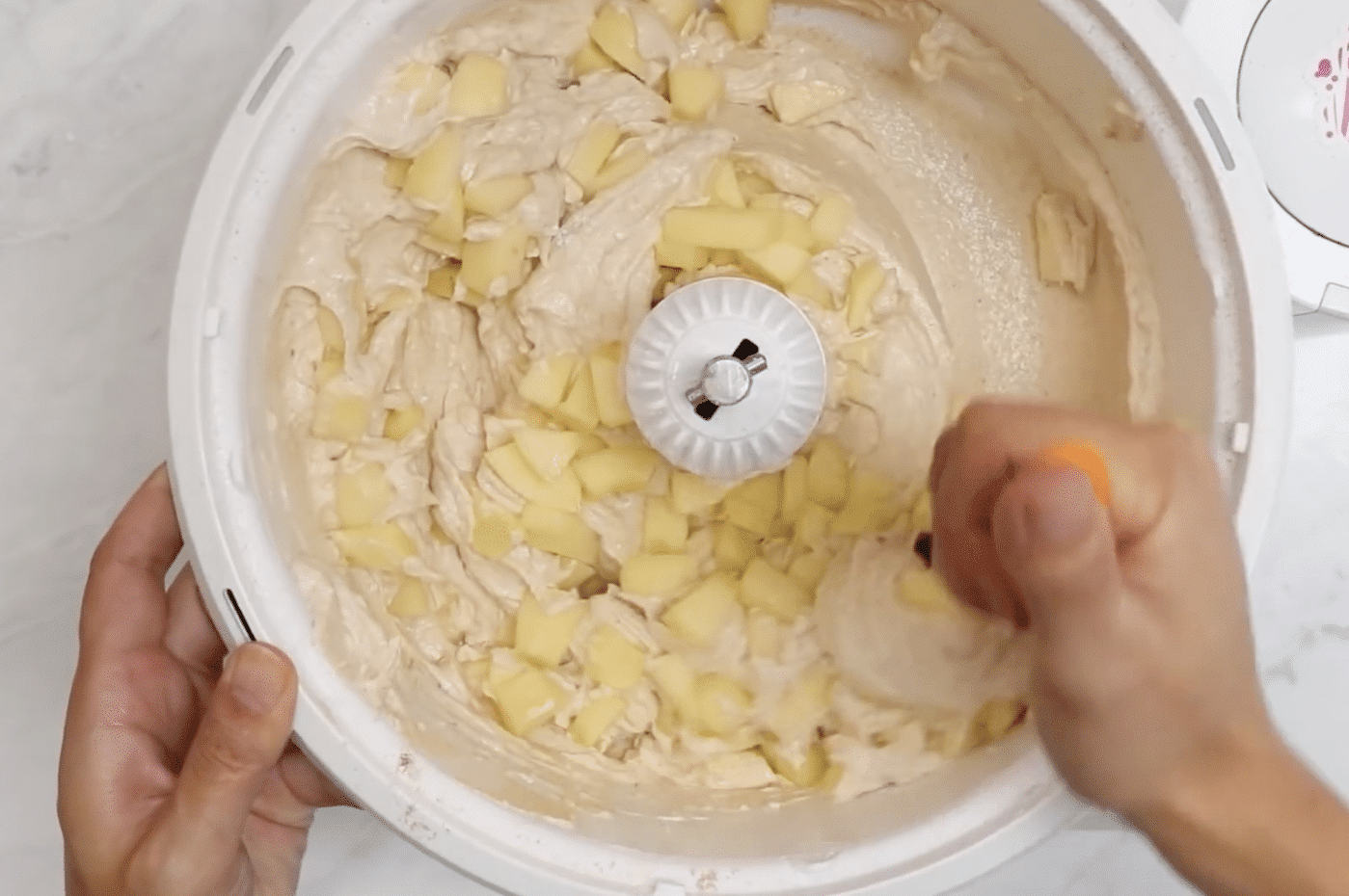 Chopped apples and applesauce being folded into the cake batter.