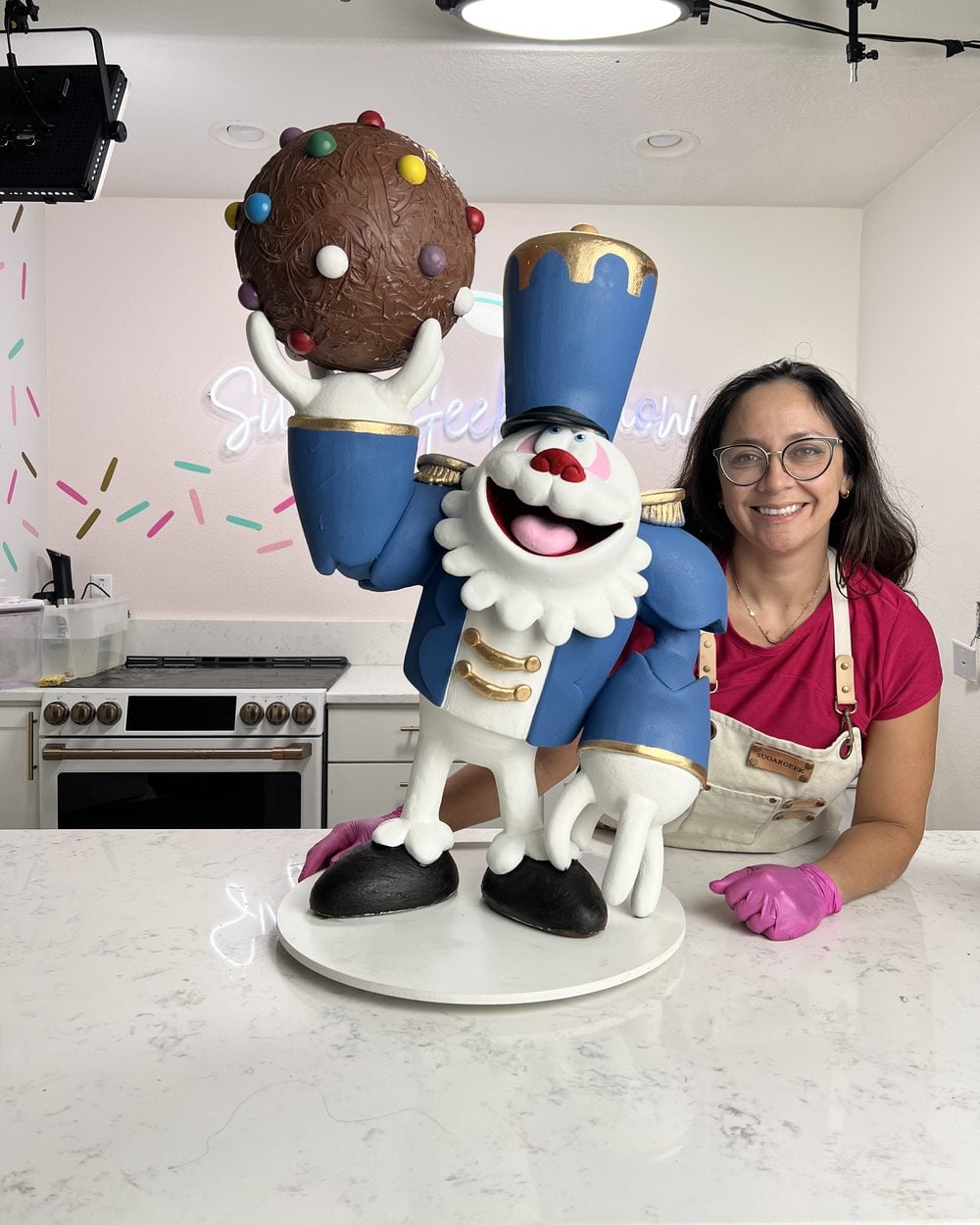 Liz Marek beside the chocolate sculpture she made for Candy Crush, a toy-soldier character holding a candy-studded chocolate ball
