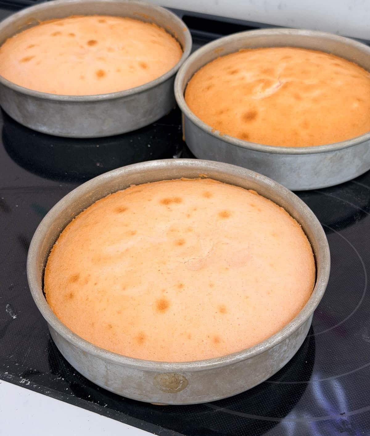 Baked pink champagne cake layers in cake pans.