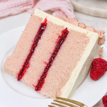 close up of pink champagne cake with raspberry filling on a white plate.