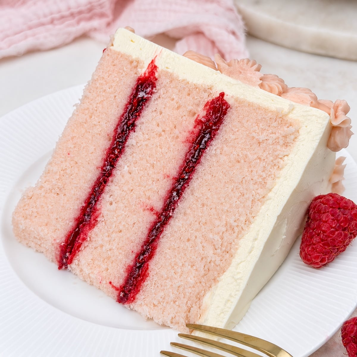 close up of pink champagne cake with raspberry filling on a white plate.