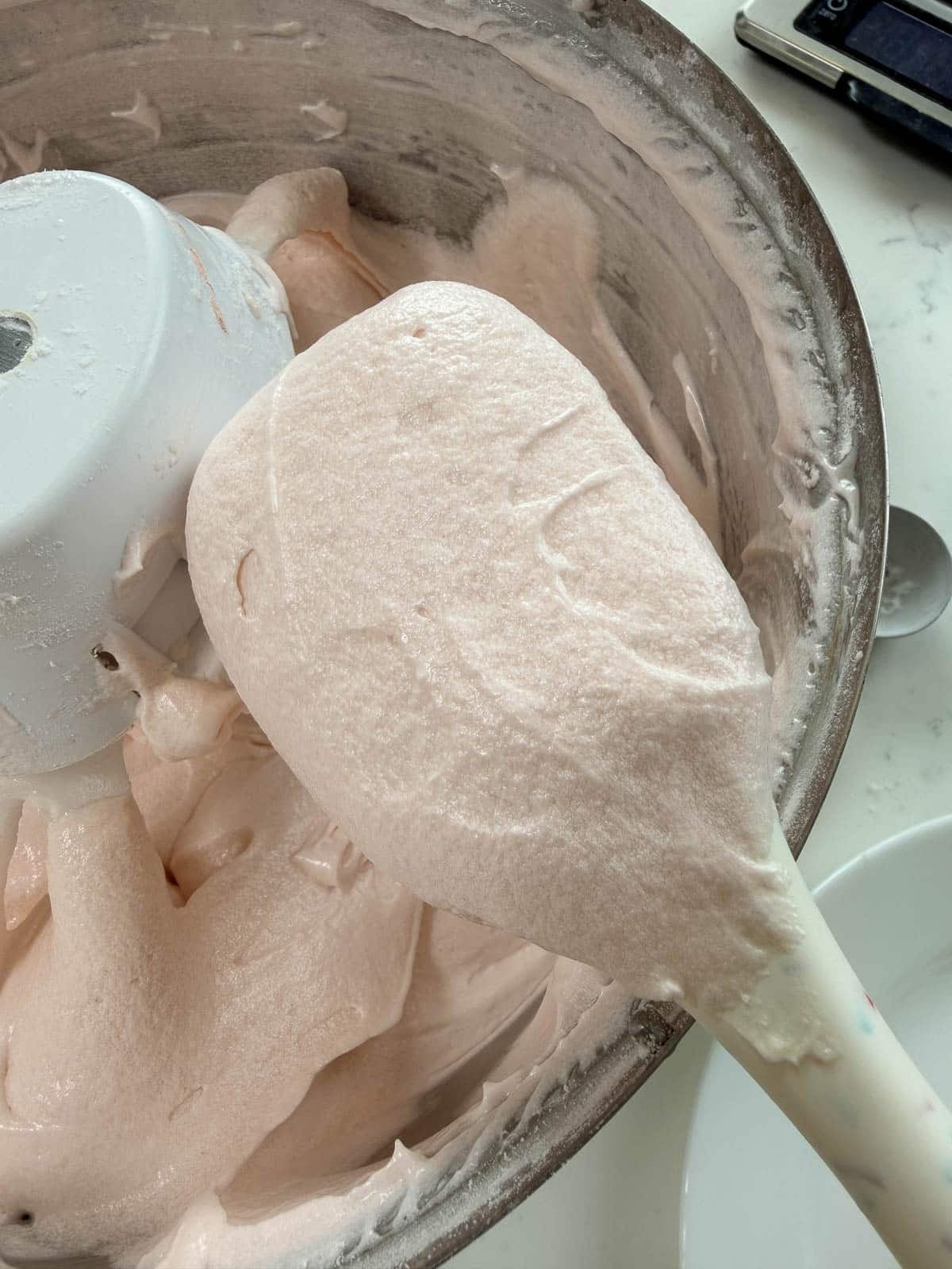 close up of mixed pink champagne cake batter on a spatula.