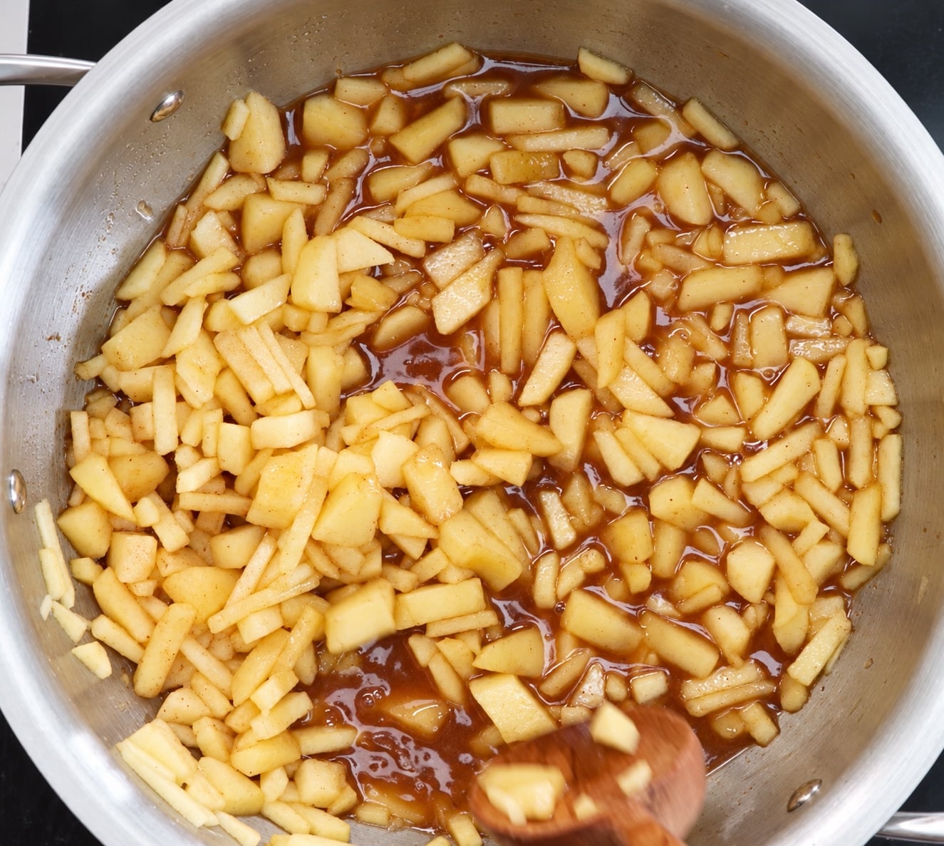 Apples simmering in spiced apple juice in a stainless steel pan