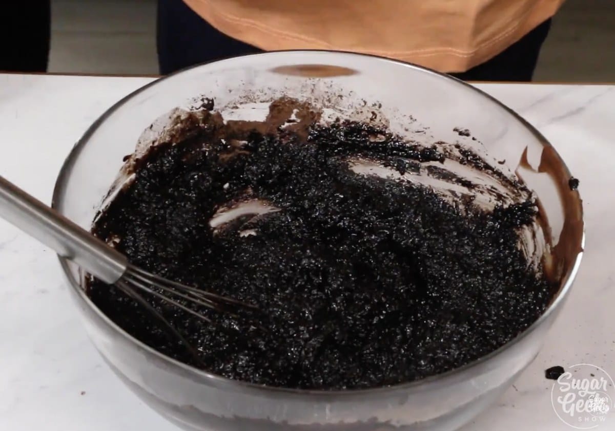Melted chocolate, black cocoa powder, coffee, and oil whisked together in a glass bowl.