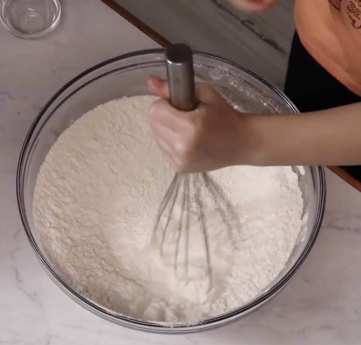 Whisking flour, baking powder, baking soda, and salt in a glass bowl.